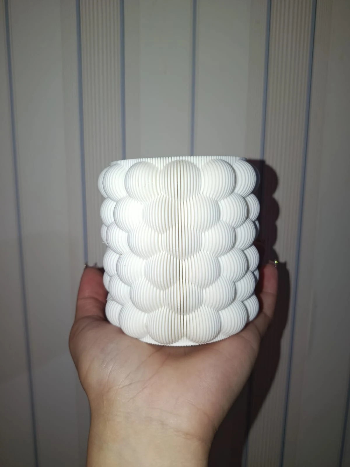 Vaso branco em impressão 3D com textura de bolhas, apoiado na mão